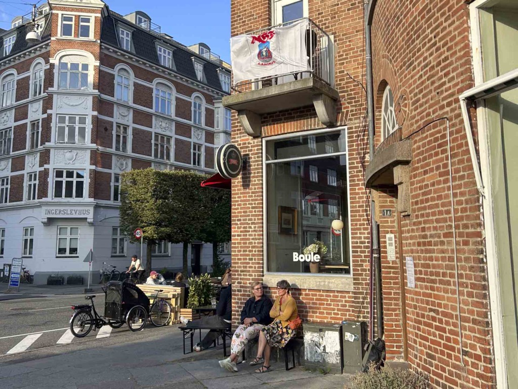 R&oslash;d murstensbygning med g&aelig;ster udenfor hos Boule i Aarhus