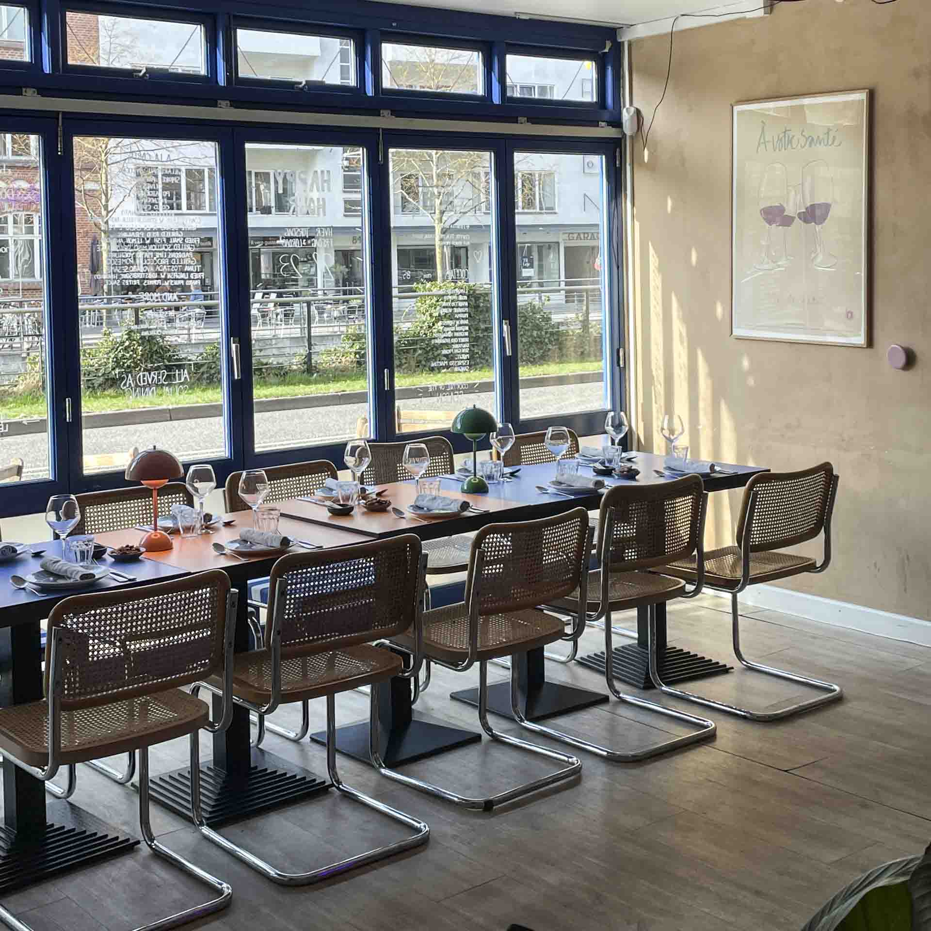 Langbord med stole ved vinduerne hos Elle Belle ved åen i Aarhus