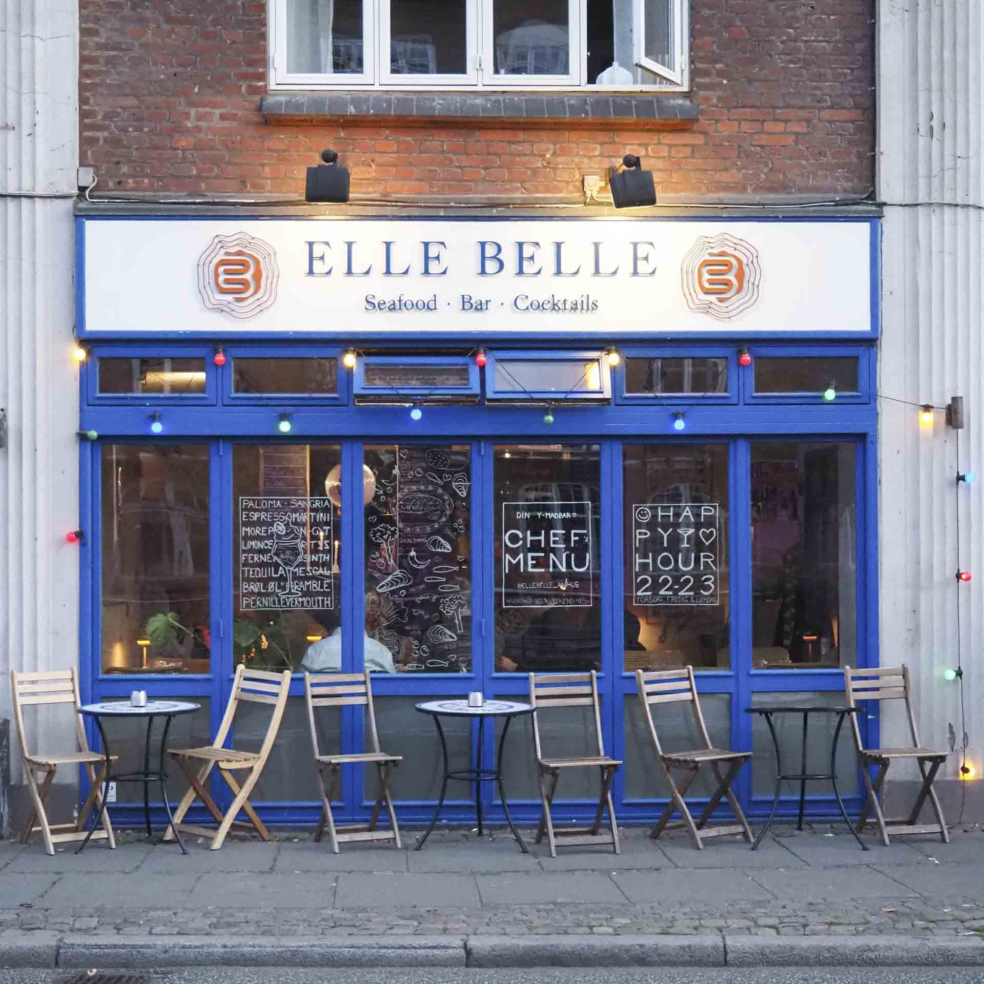 Blå facade med cafeborde foran hos Elle Belle ved åen i Aarhus