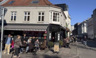 Hjørnebygning med udeservering under blå himmel hos Poco Nero i Jægergårdsgade i Aarhus