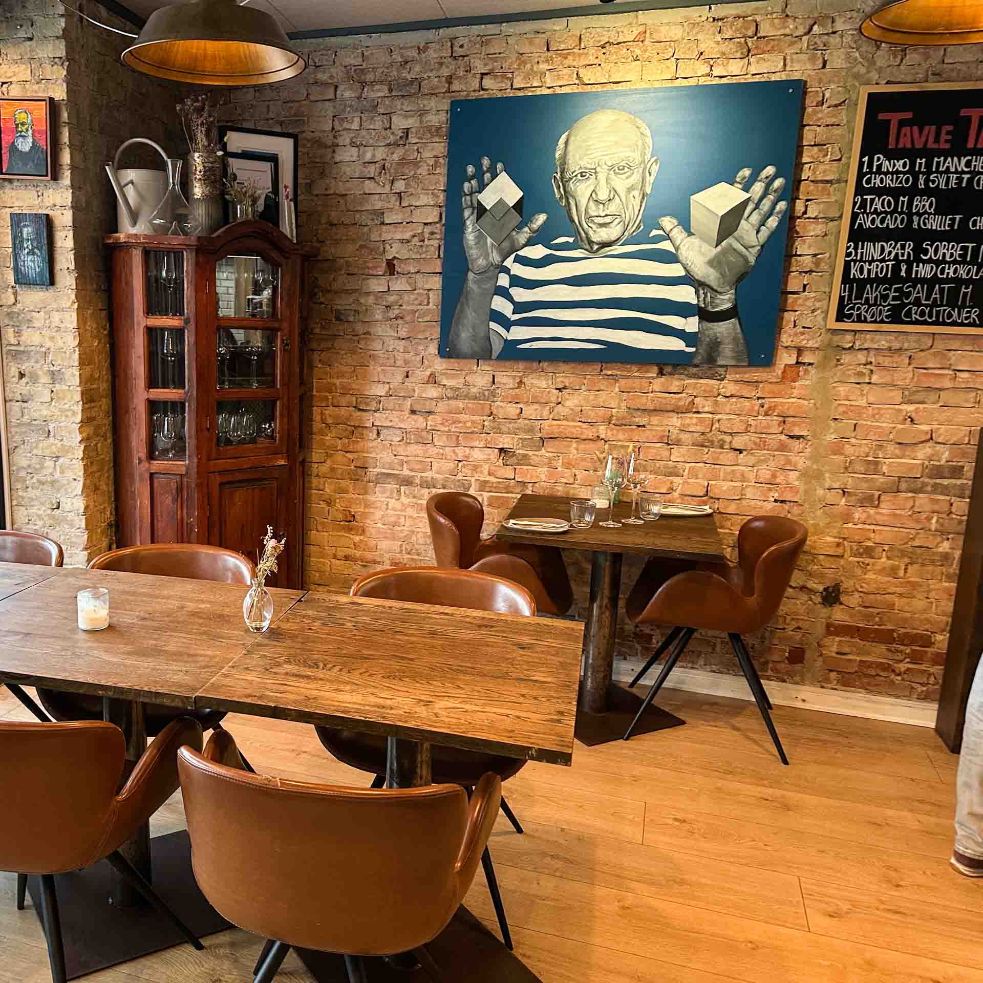 Lokalet med murstensvæg og portræt på væggen hos Restaurant Socios i Aarhus C