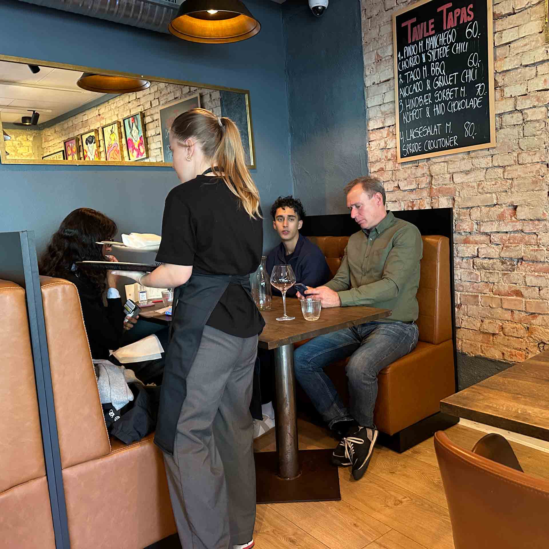 Tjener betjener gæster ved bordet hos Restaurant Socios i Aarhus C