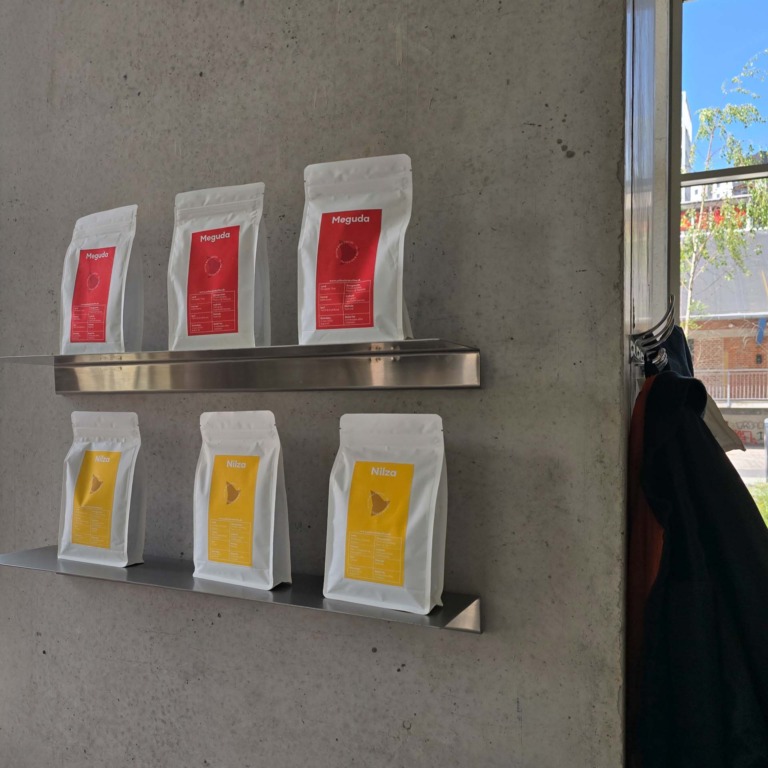 Kaffeposer i sorterne Meguda og Nilza p&aring; metalhylder p&aring; betonv&aelig;g hos F&aelig;tter p&aring; Godsbanen.
