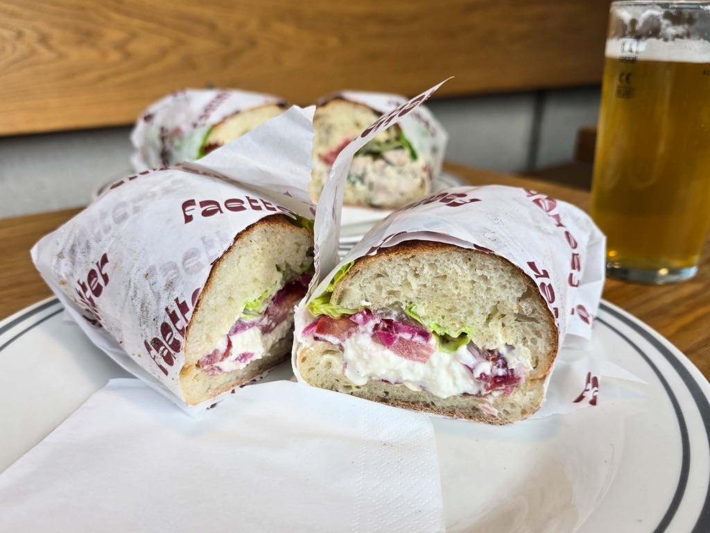 Flere sandwich med kyllingesalat og tr&oslash;ffelsalami i indpakningspapir p&aring; F&aelig;tter p&aring; Godsbanen.