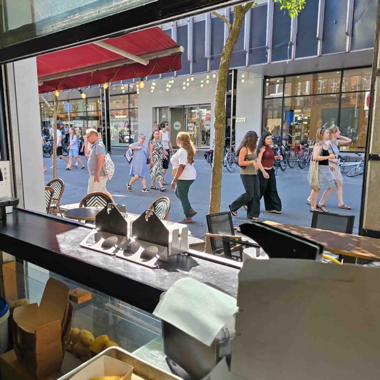 Udsigt fra Aarhus Smash mod Immervad med g&aring;ende og cyklister foran butikkerne overfor.
