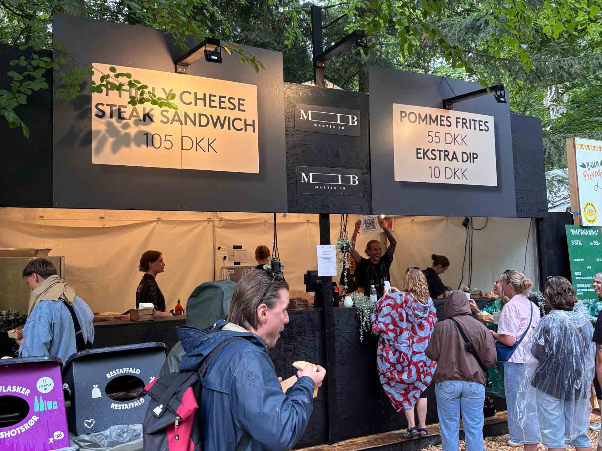 Madboden lå midt i den klassiske Smukfest-kulisse med træer, flis på jorden og festivalgæster i store mængder. Vejret var på dette tidspunkt langt fra optimalt, men det tog ikke energien ud af området.