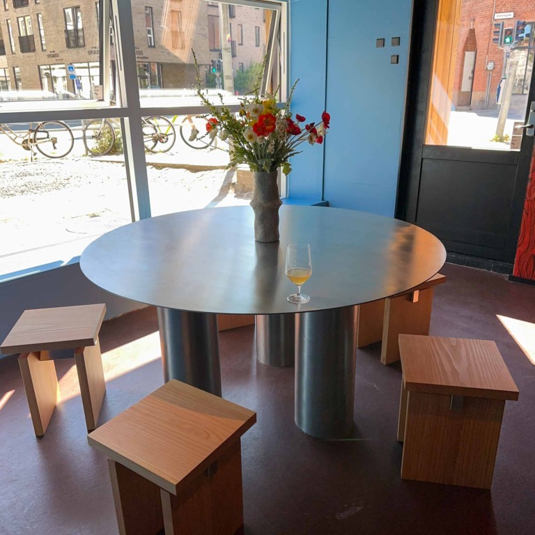 Rundt st&aring;lbord med blomster og tr&aelig;skamler hos Ratata Bar i N&oslash;rre All&eacute; i Aarhus