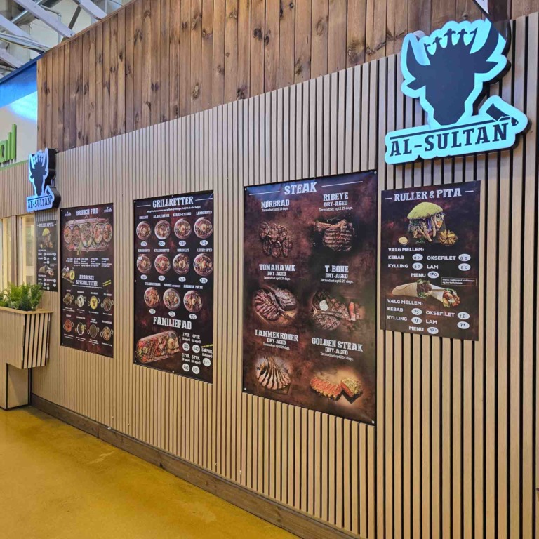 Skilt og menuplakater ved indgangen hos Al Sultan i Brabrand