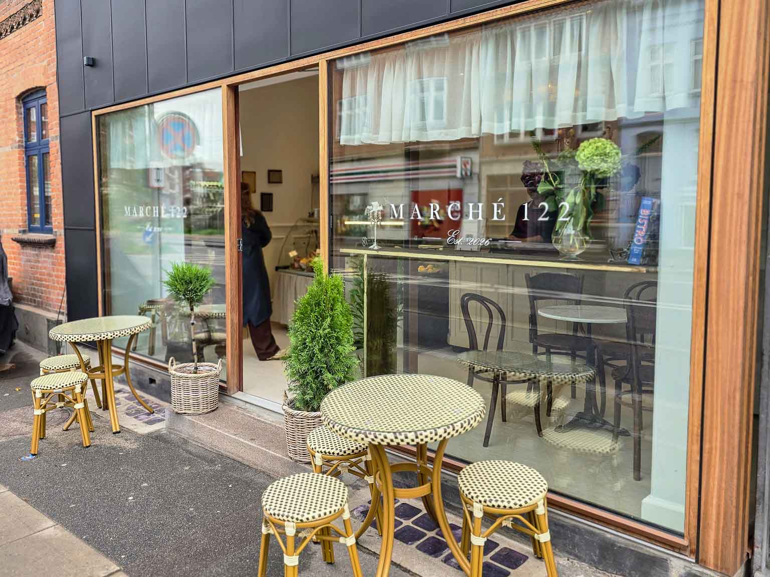 Indgang og udeservering med små borde hos Marché 122 i Aarhus C
