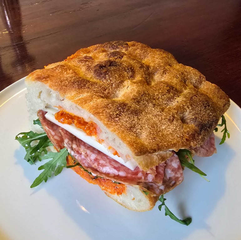 Focaccia-sandwich med salami, ost og rucola p&aring; tallerken hos March&eacute; 122 i Aarhus C