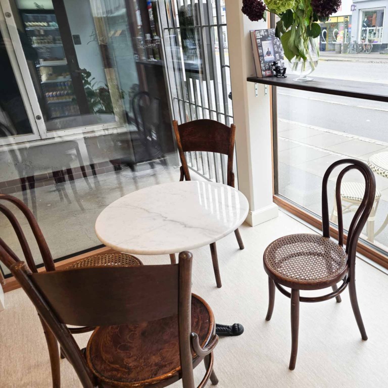 Rundt marmorbord og caf&eacute;stole ved vinduet hos March&eacute; 122 i Aarhus C