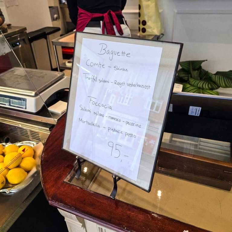 H&aring;ndskrevet skilt i ramme p&aring; disken hos March&eacute; 122 i Aarhus C