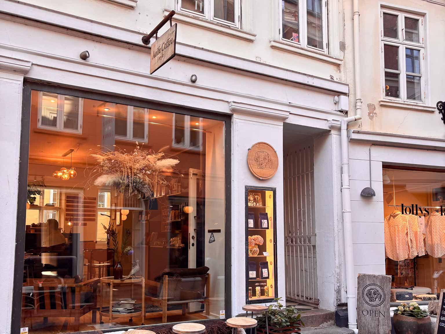 Vinduesparti med varmt lys og skilt på muren hos Aoife Coffee i Volden i Aarhus C