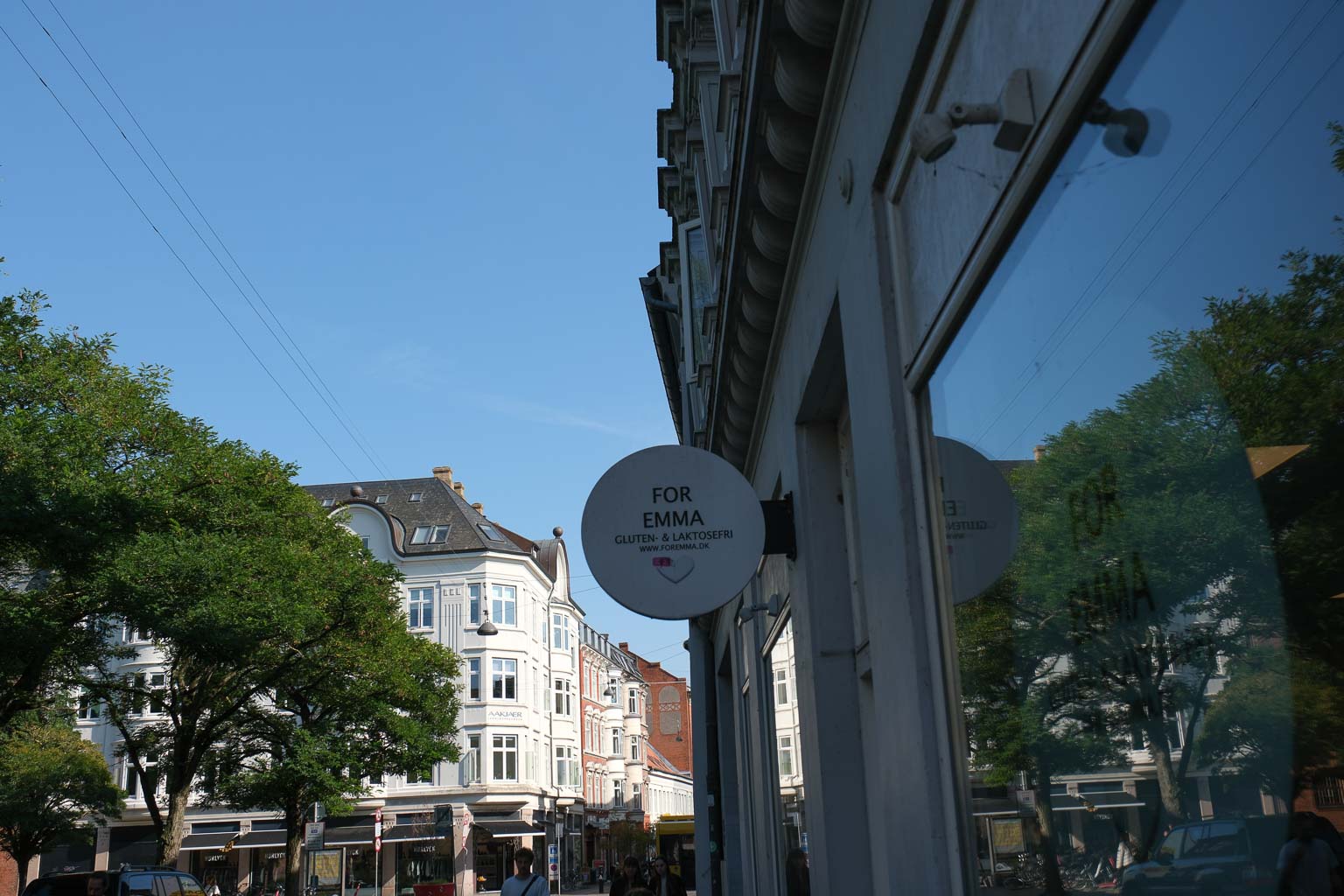 Rundt skilt på facaden og udsigt ned ad gaden hos Aoife Coffee i Volden i Aarhus C