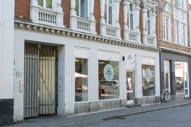 Lys facade i gaden med rundt skilt hos Aoife Coffee i Volden i Aarhus C