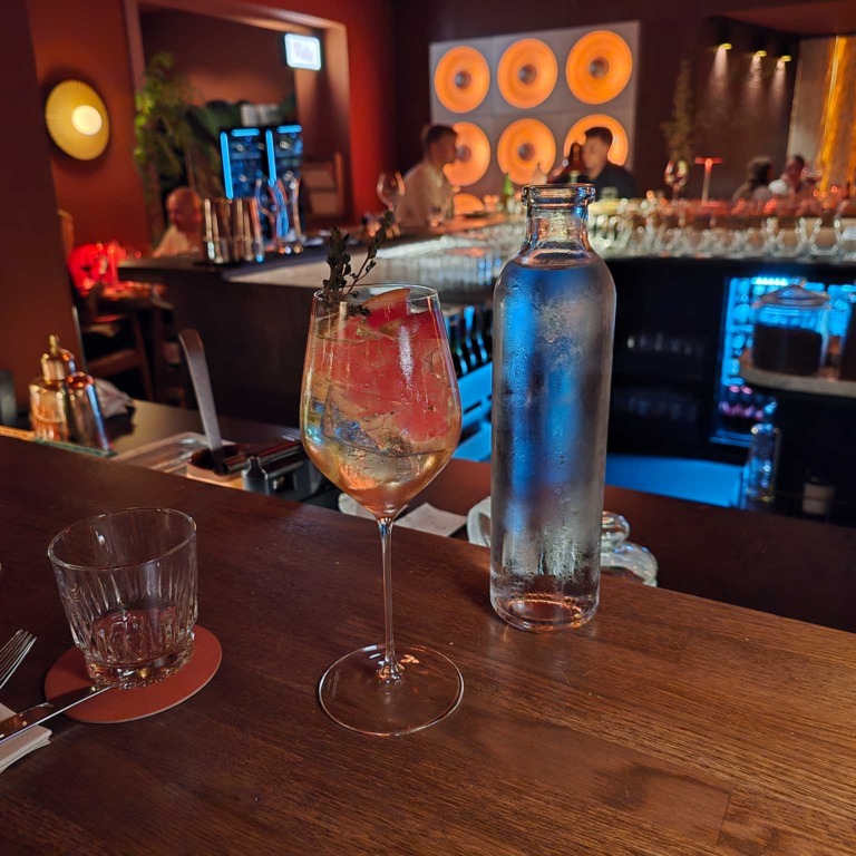 Vinglas og vandkaraffel med baren i baggrunden hos Boca R&eacute;al