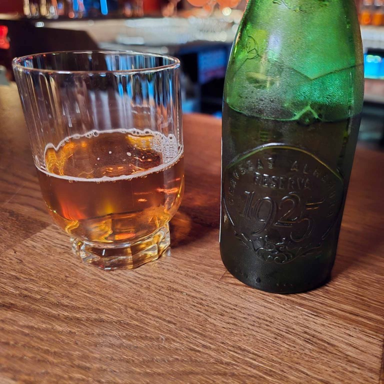 Glas med lys drik og gr&oslash;n flaske hos Boca R&eacute;al