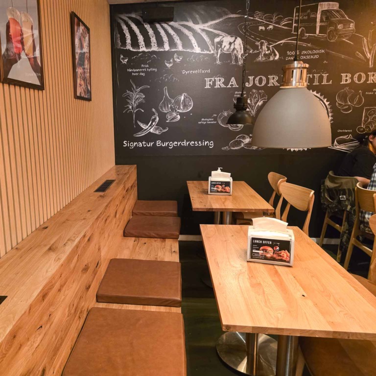 Tr&aelig;b&aelig;nk og borde under tavlev&aelig;g hos Burger Boom p&aring; Tr&oslash;jborg