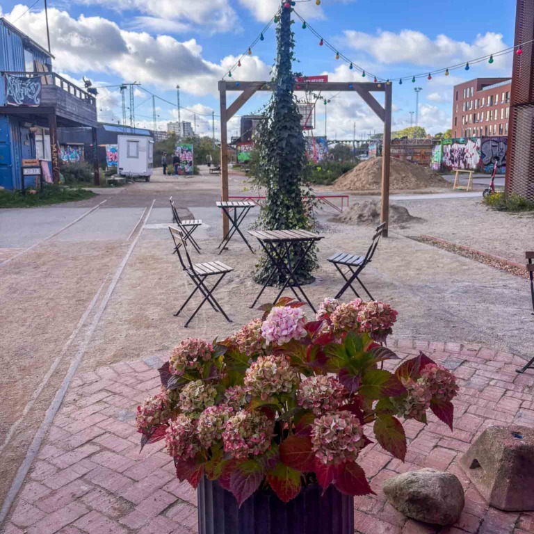 Caf&eacute;borde og blomster mellem containerne hos Institut for X