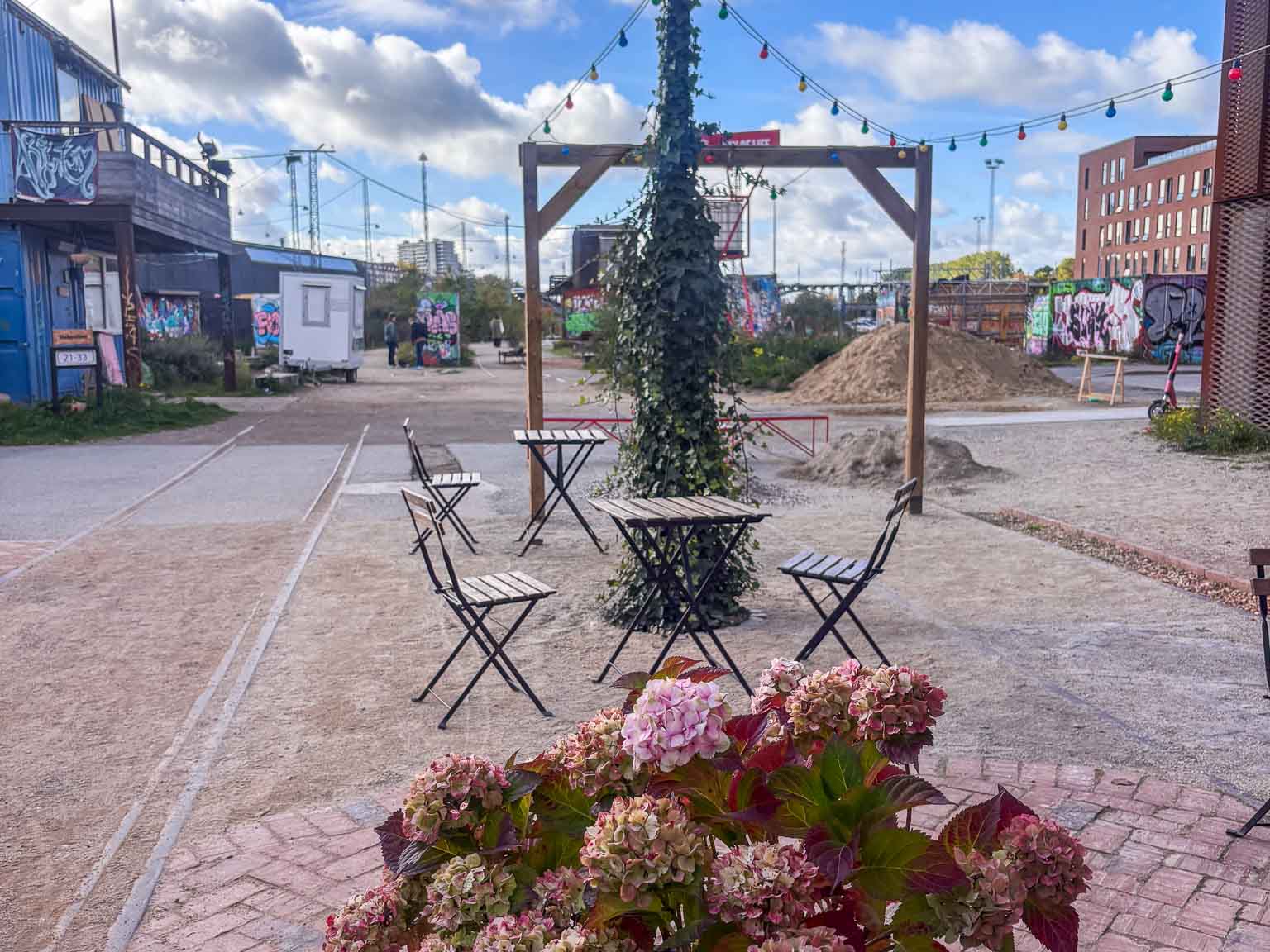Caféborde og blomster mellem containerne hos Institut for X